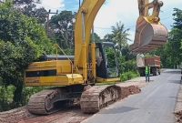 Alat berat excavator terlihat sibuk membongkar ruas jalan yang rusak di Desa Mandeu, Kabupaten Belu.